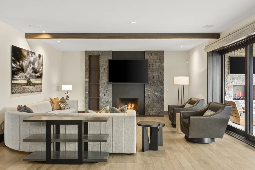 A luxury remodel of a living room with earthy highlights (stone fireplace, wood floors) as well as clean lines to help illustrate luxury home trends.