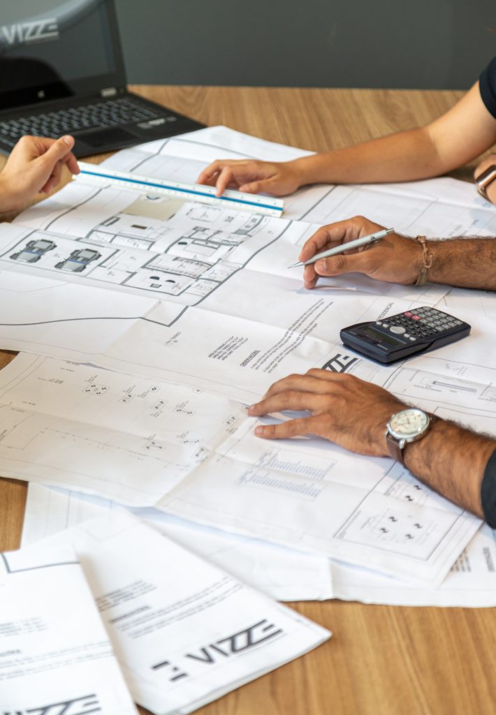 Home Design Studio Presentation: A group of people looking over plans at a table to help illustrate benefits of an interior designer.