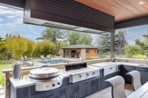 An incredible outdoor kitchen overlooking a pool to help illustrate luxury home essentials and luxury outdoor kitchen designs
