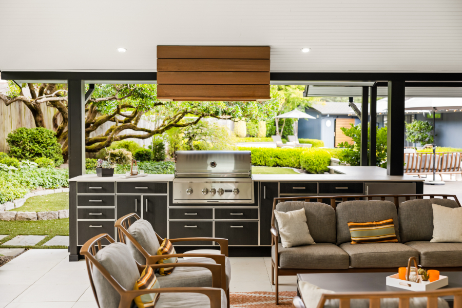 Luxury outdoor kitchen and seating space looking out onto the backyard with seamless flow to help illustrate how to plan an outdoor living space