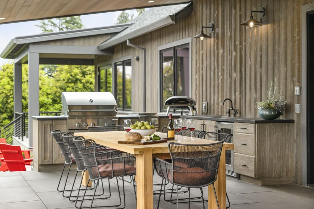 Outdoor kitchen area with grill, countertops, sink, etc., dining area, and seating area to help illustrate Does Outdoor Living Space Add Value?